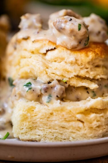 close up of a split biscuit with the pieces stacked and sausage gravy on top and between.