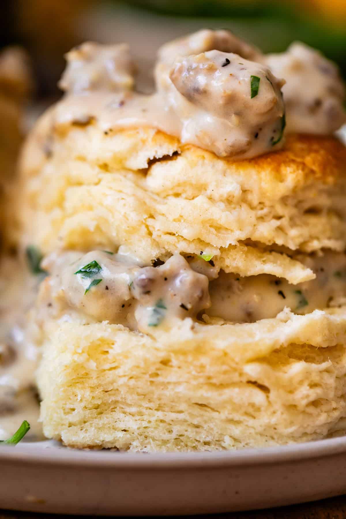 close up of a split biscuit with the pieces stacked and sausage gravy on top and between.