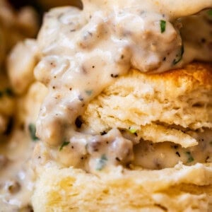 close up of a split biscuit with the pieces stacked and sausage gravy on top and between.