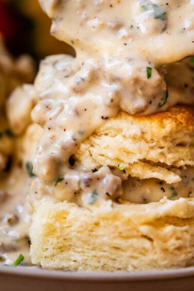 close up of a split biscuit with the pieces stacked and sausage gravy on top and between.