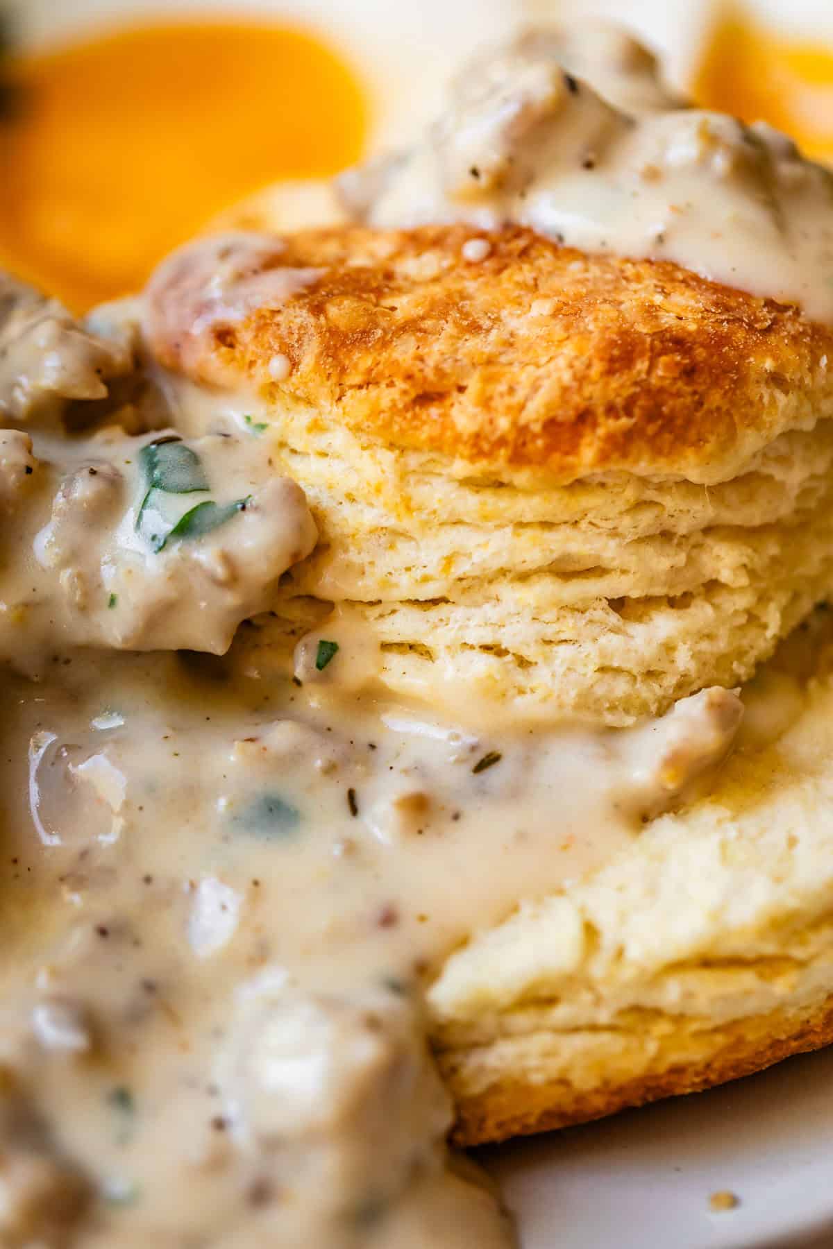 close up of a split biscuit with the pieces stacked and sausage gravy on top and between.