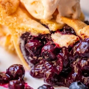 picture of a slice of blueberry pie with lattice crust and ice cream.