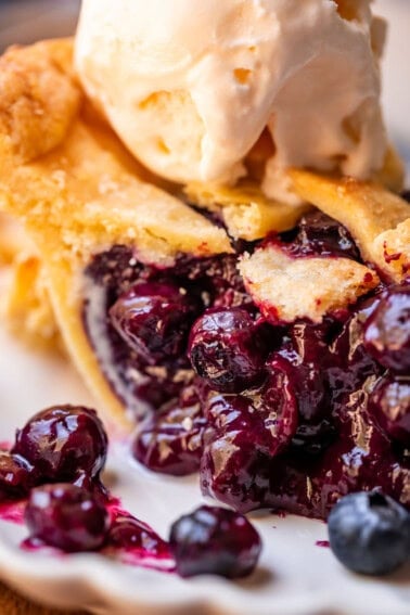 picture of a slice of blueberry pie with lattice crust and ice cream.