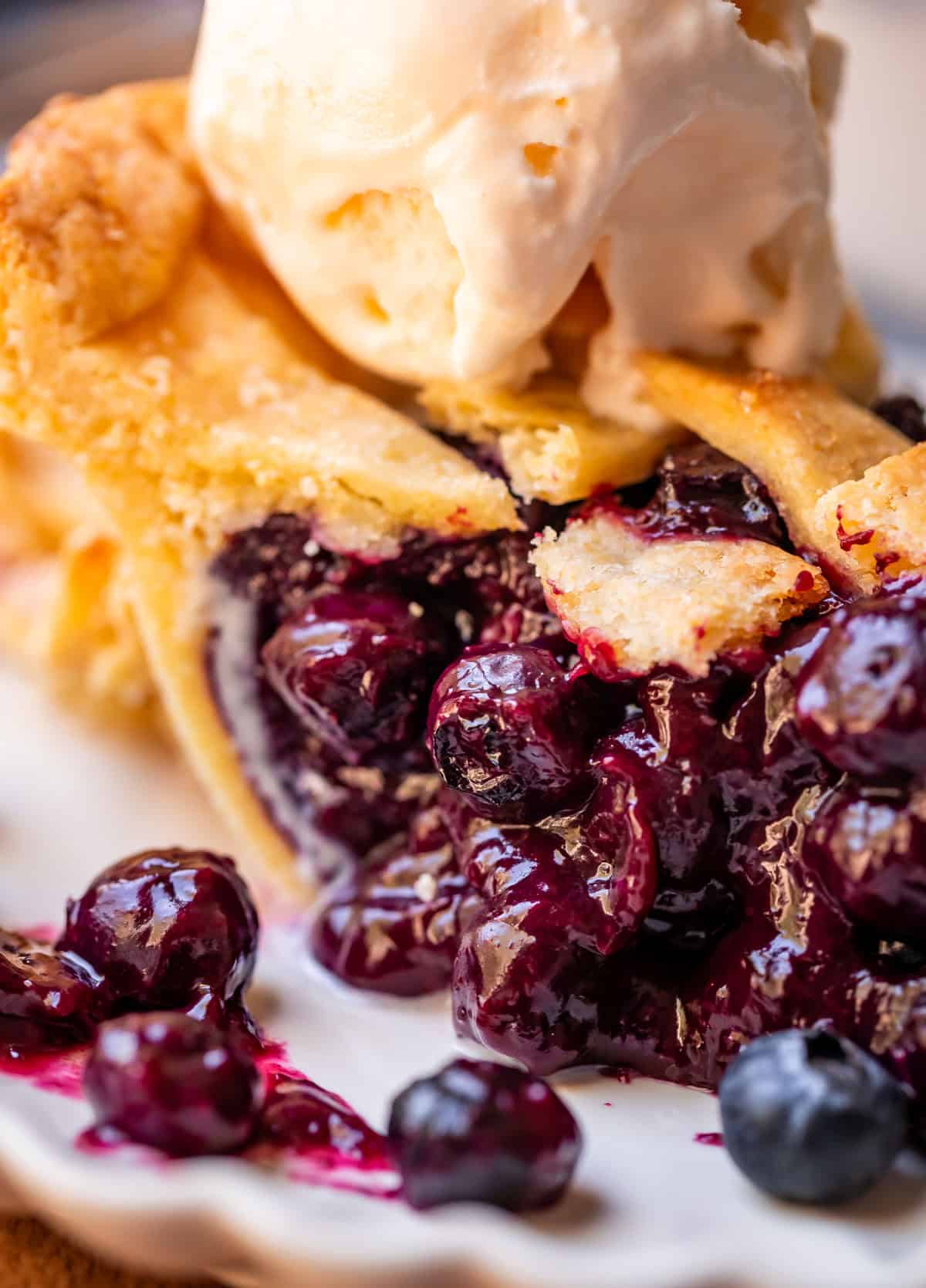 picture of a slice of blueberry pie with lattice crust and ice cream.