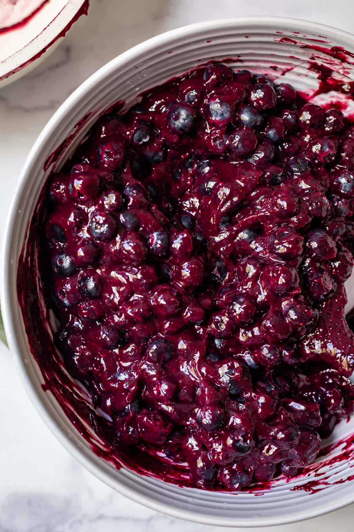 overhead shot of blueberry pie filling in a white ceramic bowl.