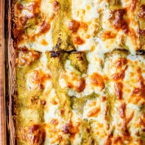 looking down at a glass casserole dish of baked green chicken enchiladas,