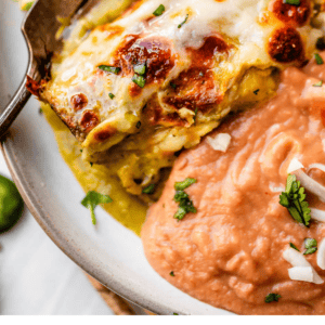 pinterest image of an enchilada plate with beans and text "restaurant quality chicken enchiladas".