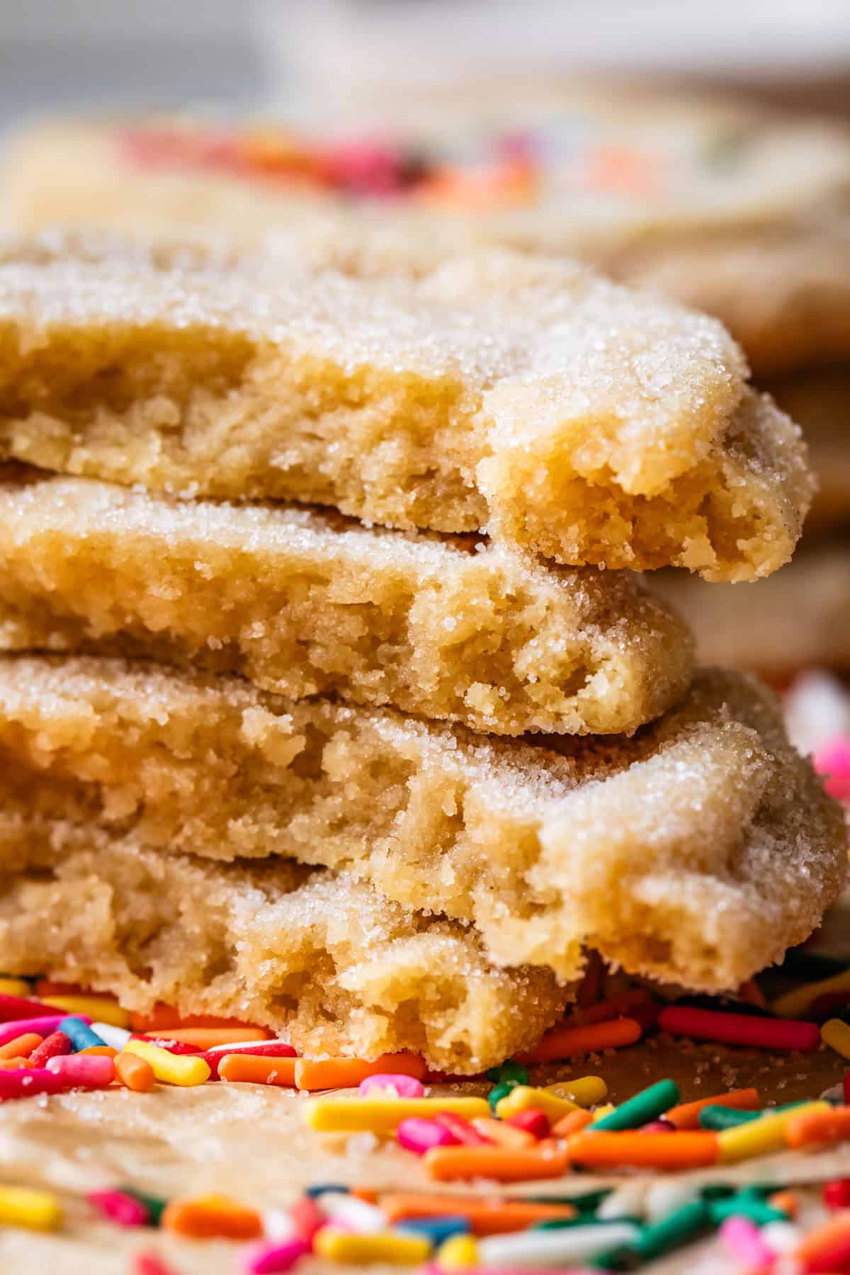 four stacked no roll sugar cookies broken in half to see the tender crumb.