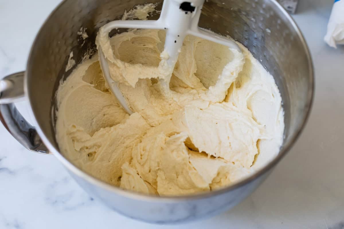 butter and cream cheese beaten together in a metal mixing bowl with a paddle attachment.