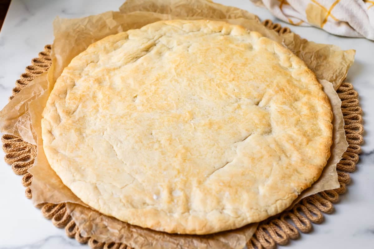 a circle of baked cookie dough crust on parchment paper on a place mat.
