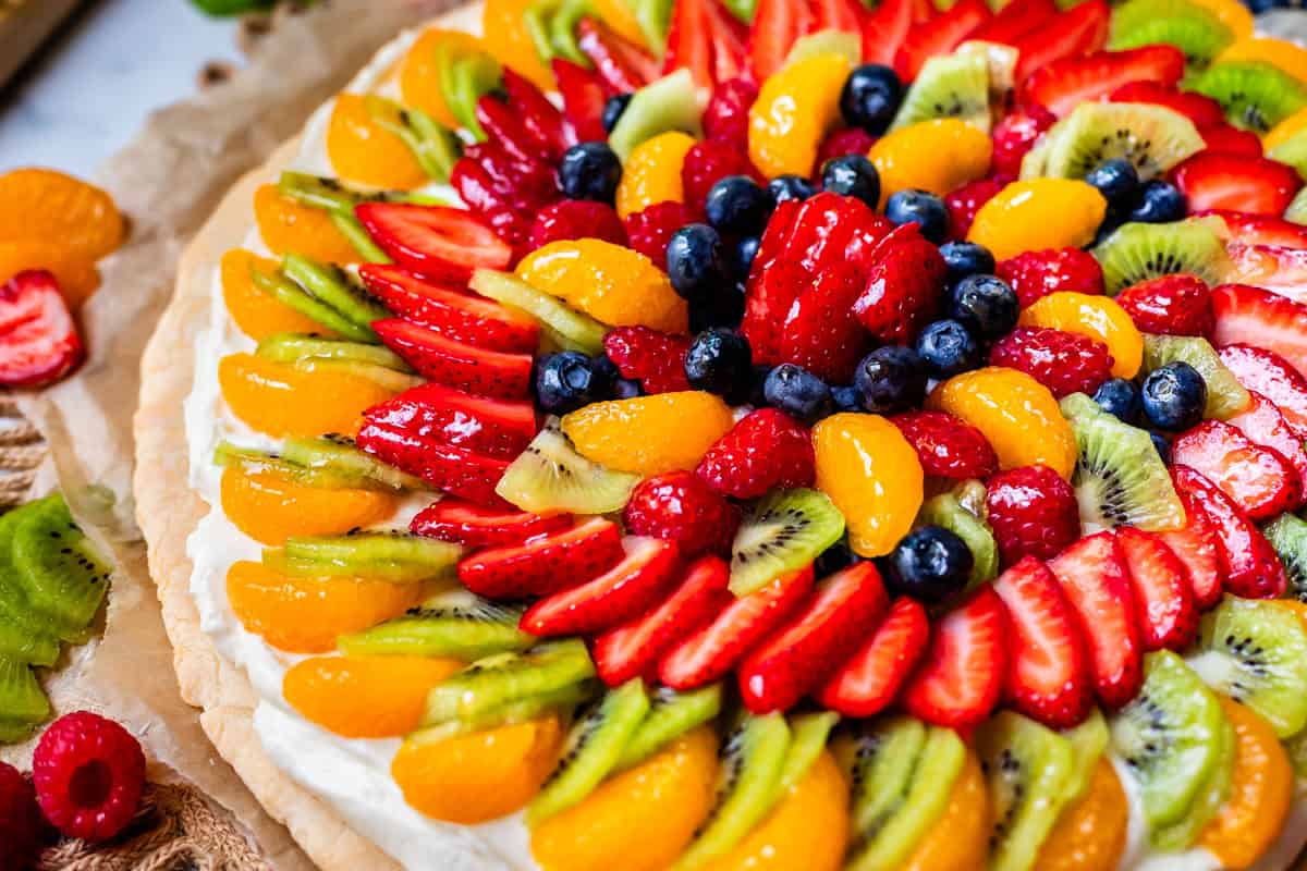 an whole circle of fruit pizza: cookie crust, frosting, and fruit with glaze.