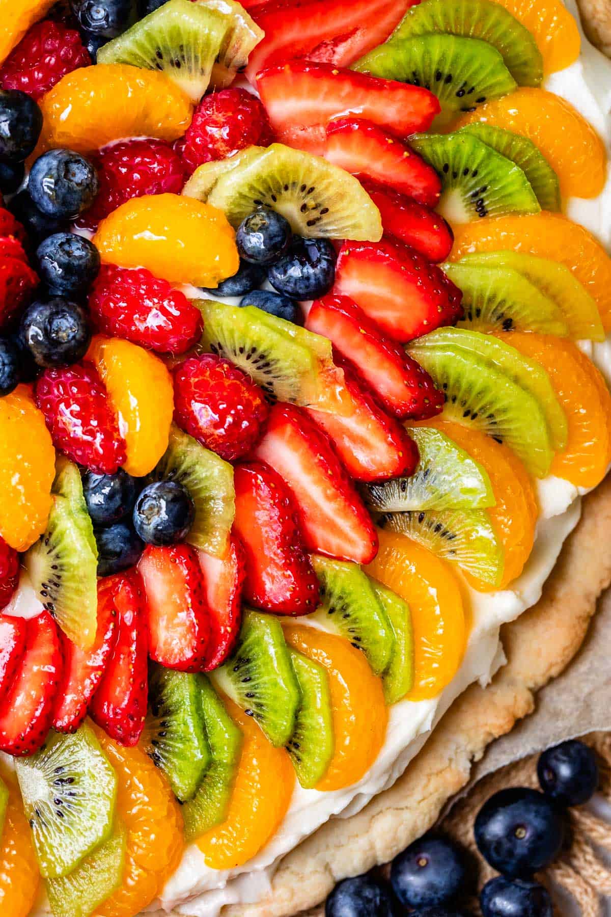 close up of fruit pizza on a circle crust showing the many layers of fruit.