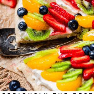 Pie server lifting a slice of fruit pizza from parchment paper.