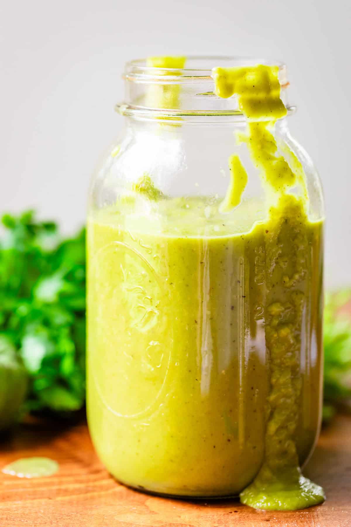 a quart sized mason jar filled 3/4s of the way with green enchilada sauce.