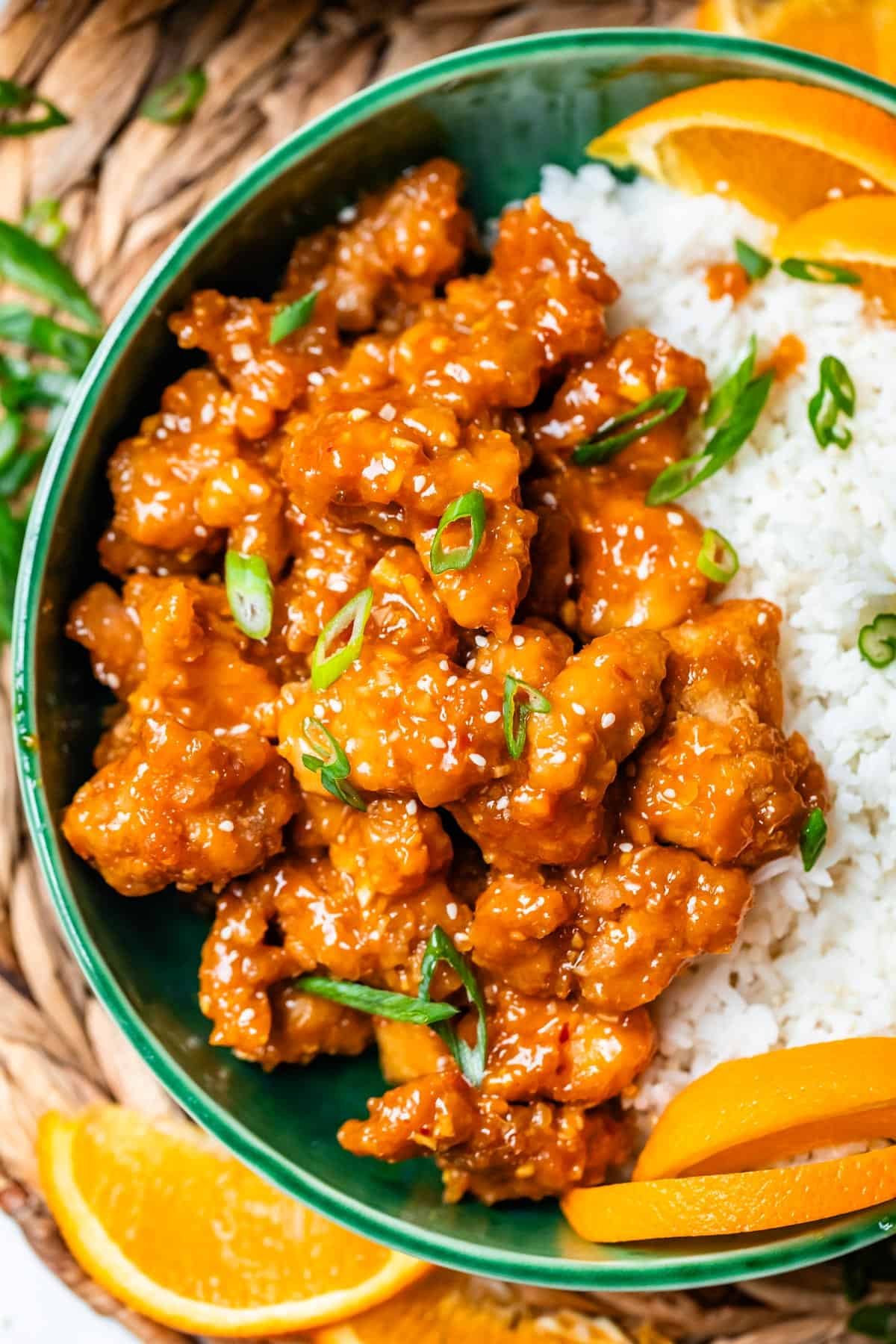 crispy orange chicken with green onion garnish in ceramic bowl.