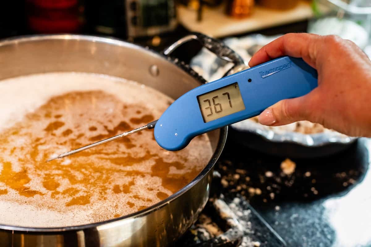 hand holding instant read thermometer to check the temperature of the oil.