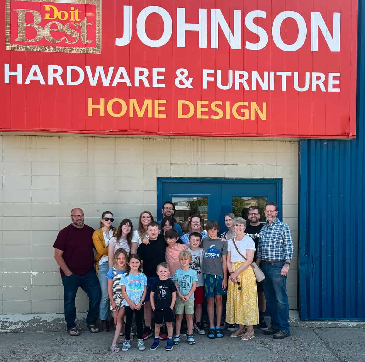 family gathered around a sign for Johnson Hardware and Furniture.