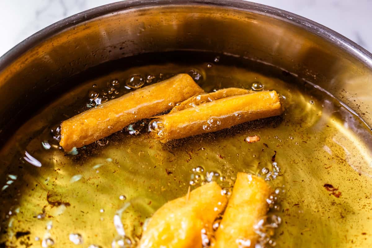 several flautas frying in about 1 inch of oil in a skillet.