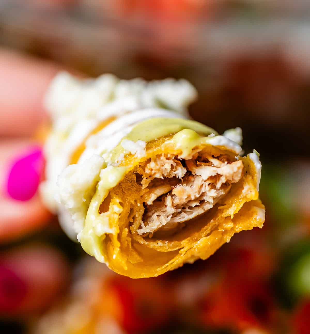 side view of a chicken flauta with a bite taken from it, showing the chicken inside.