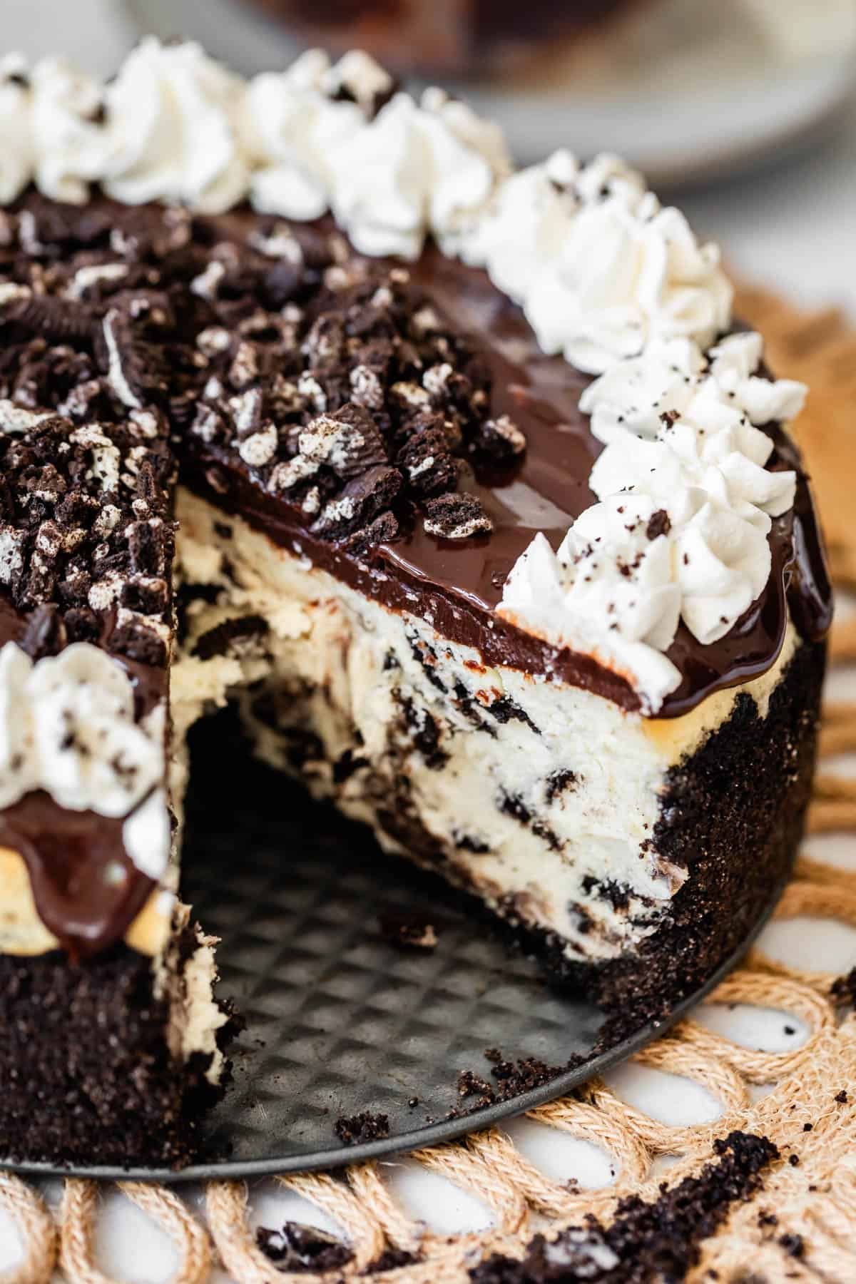 ganache & cream topped oreo cheesecake with oreo crust with a slice removed.