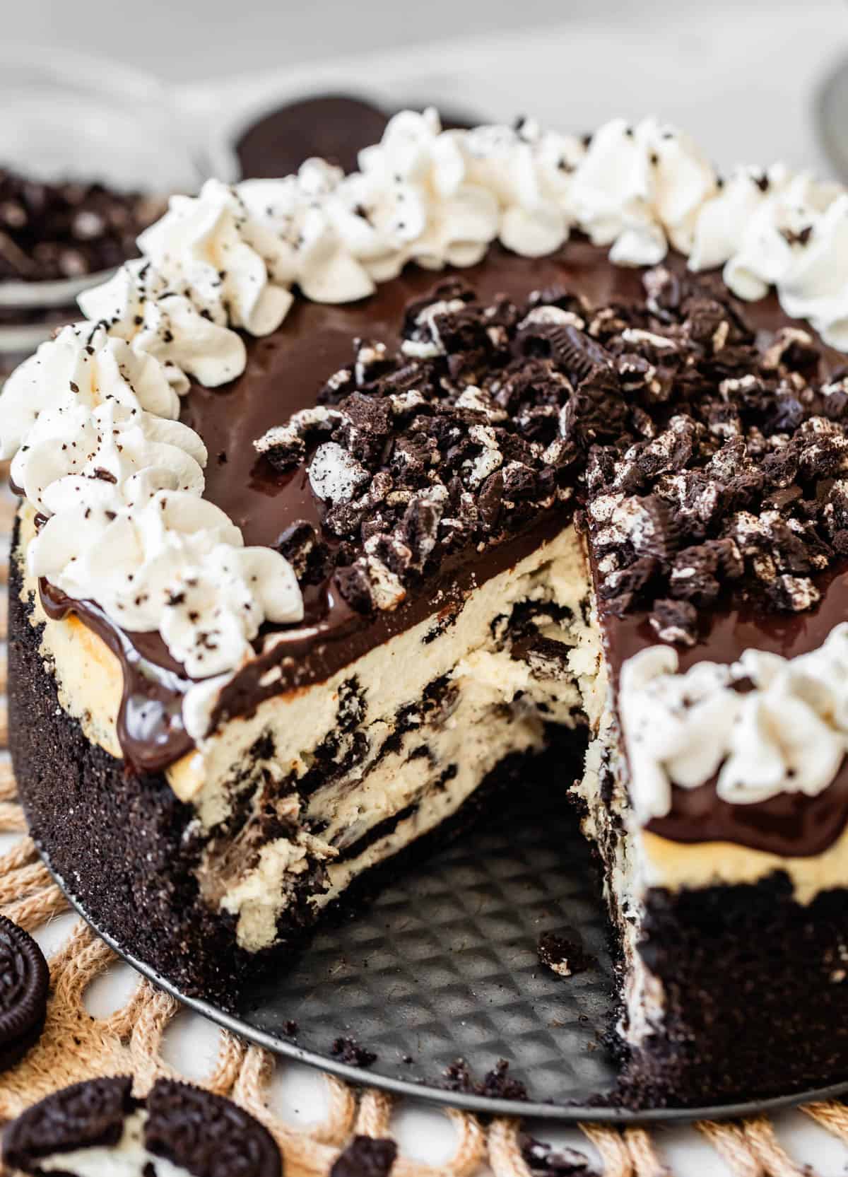 top view of a ganache topped oreo cheesecake with oreo crust with a slice removed.