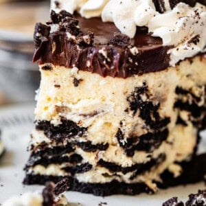 slice of oreo cheesecake with oreo crust, ganache, and whipped cream and a bite taken from it.