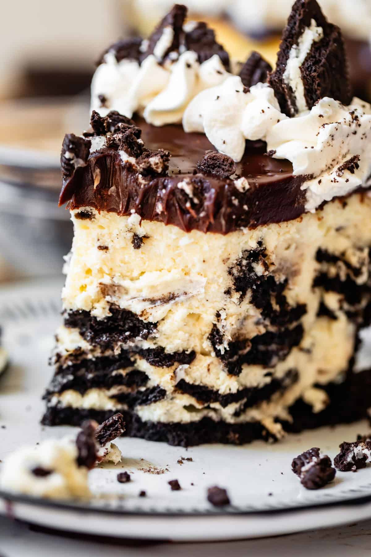 slice of oreo cheesecake with oreo crust, ganache, and whipped cream and a bite taken from it.