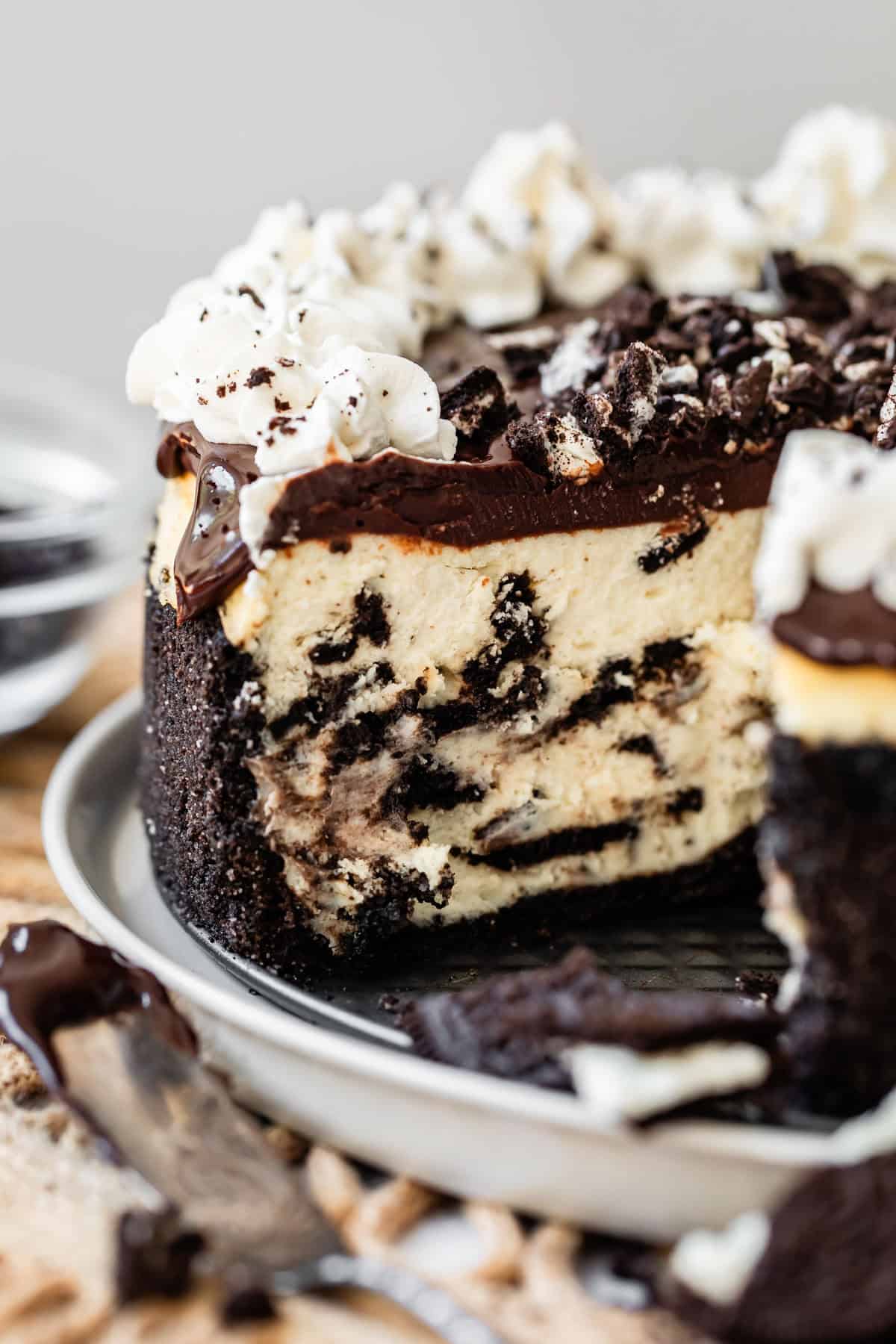 ganache topped oreo cheesecake with oreo crust with a slice removed.