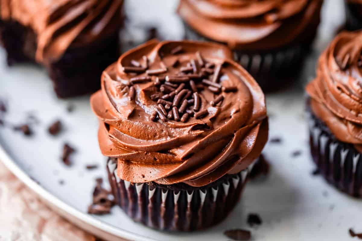 side view of a chocolate cupcake topped with piped chocolate frosting and sprinkles.