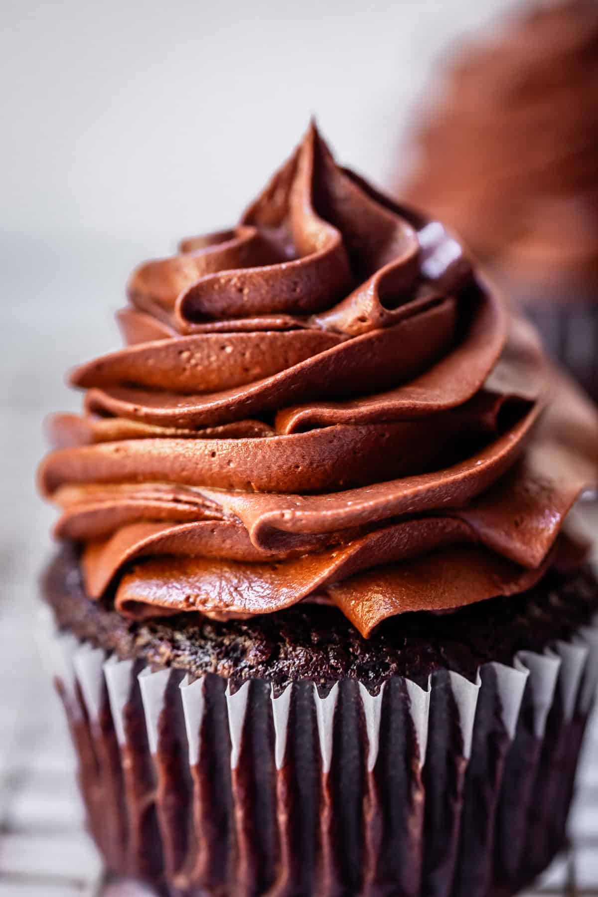 perfectly piped chocolate frosting atop a chocolate cupcake in a paper liner.