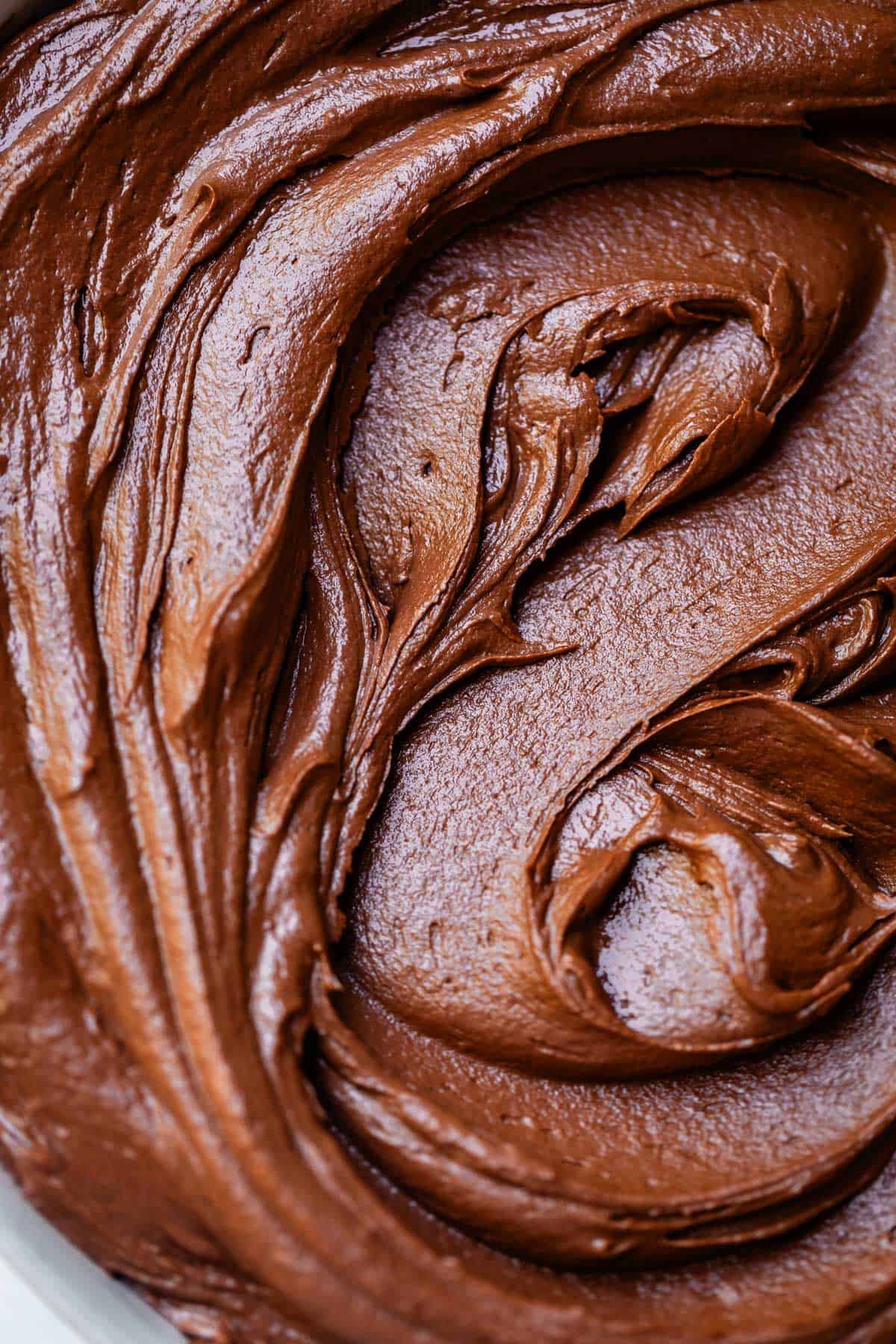 overhead shot looking down at swirled, creamy chocolate buttercream frosting in a bowl.