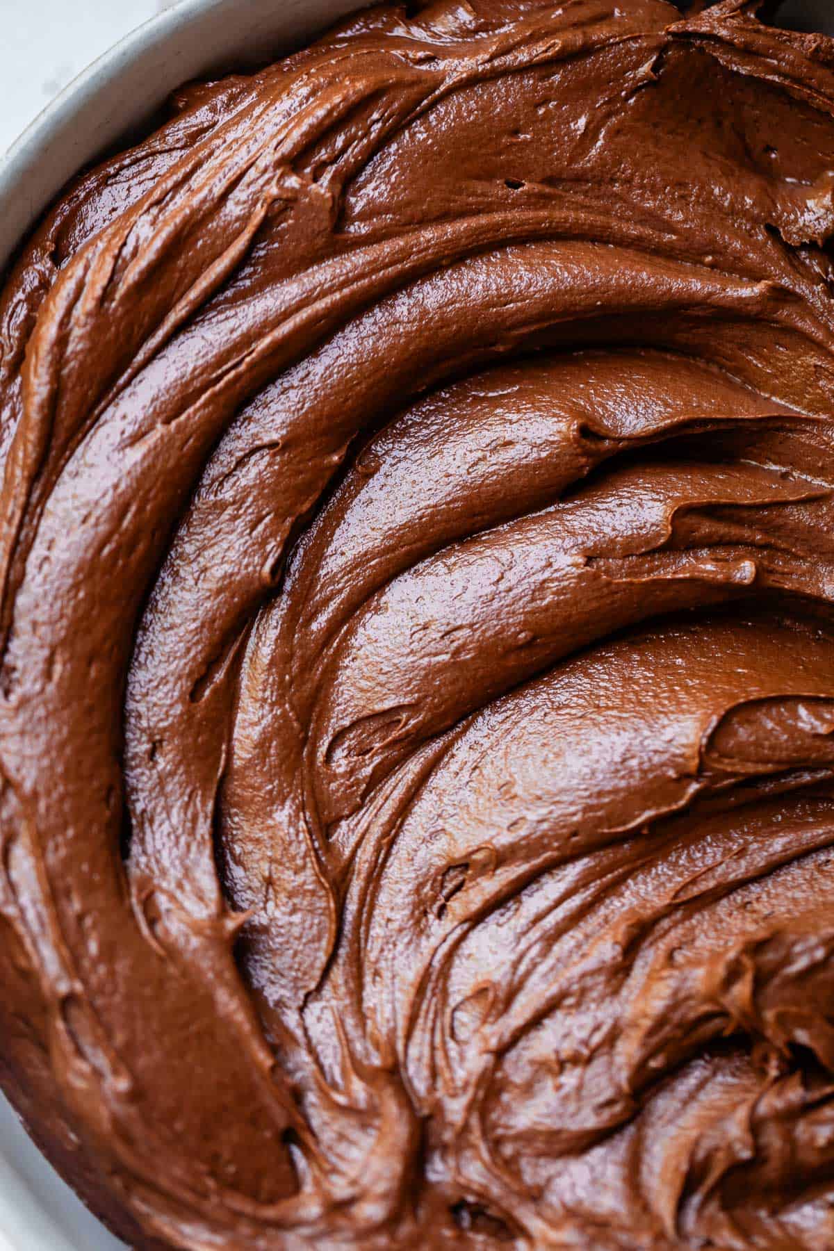overhead shot looking down at swirled, creamy chocolate buttercream frosting in a bowl.