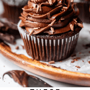 chocolate cupcakes with chocolate icing sitting on a wooden plate.