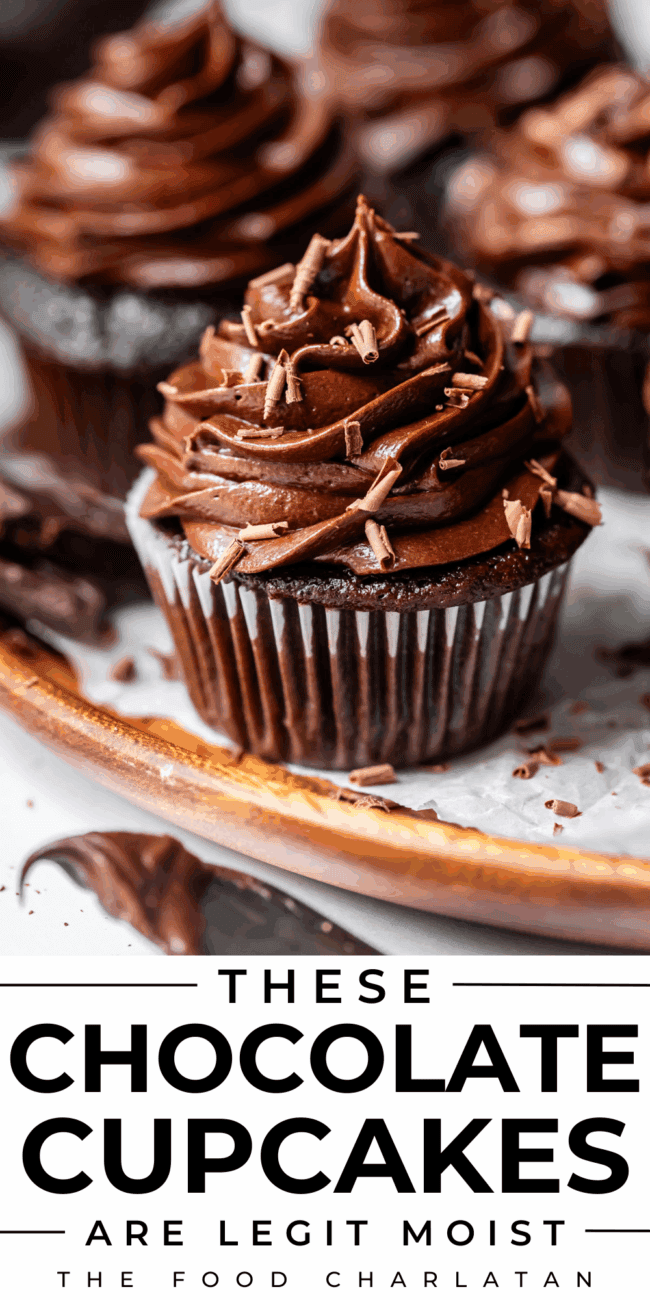 chocolate cupcakes with chocolate icing sitting on a wooden plate.