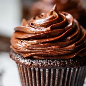 chocolate cupcake in liner topped with piped chocolate frosting.