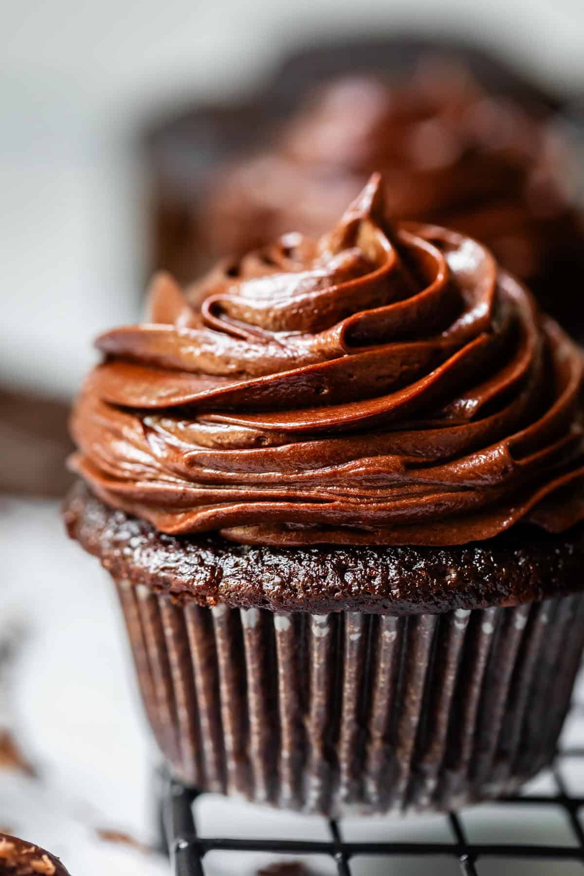 chocolate cupcake in liner topped with piped chocolate frosting.
