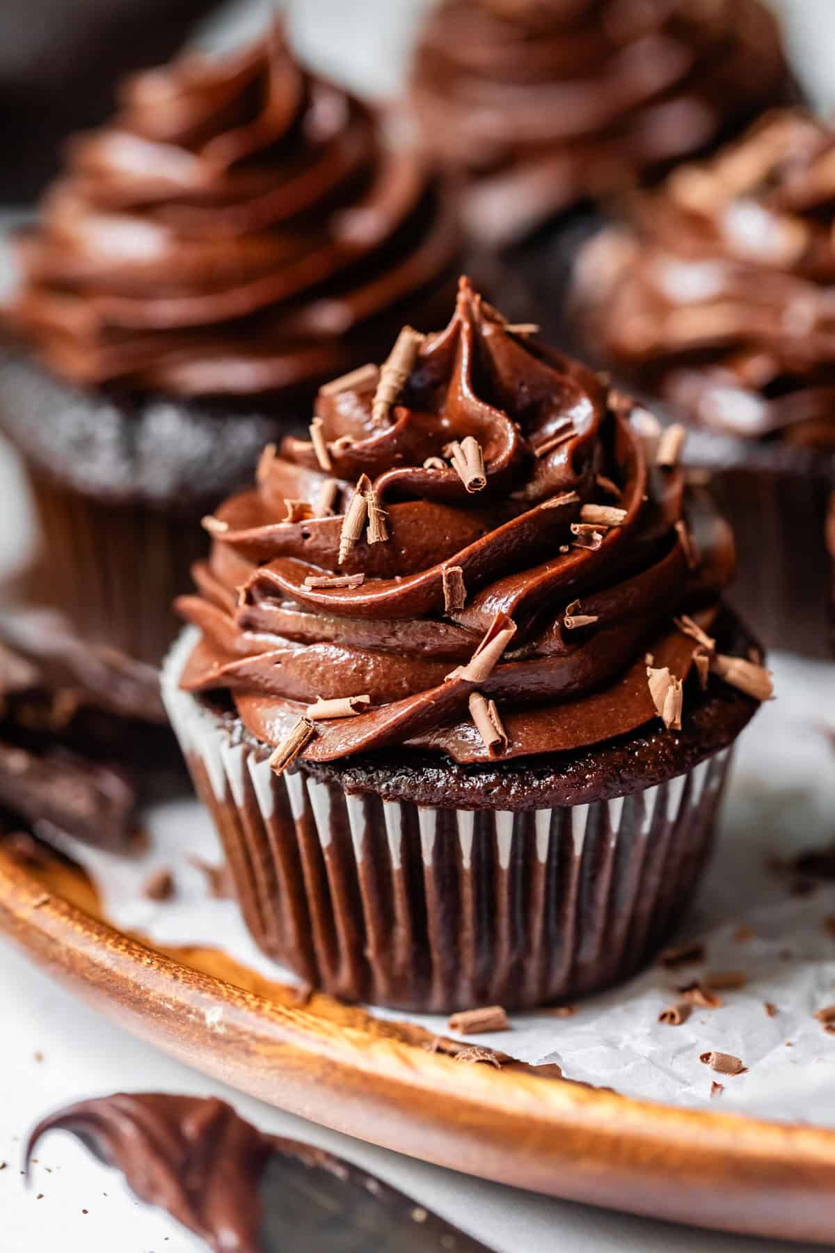 chocolate cupcake in liner topped with piped chocolate frosting and chocolate shavings.