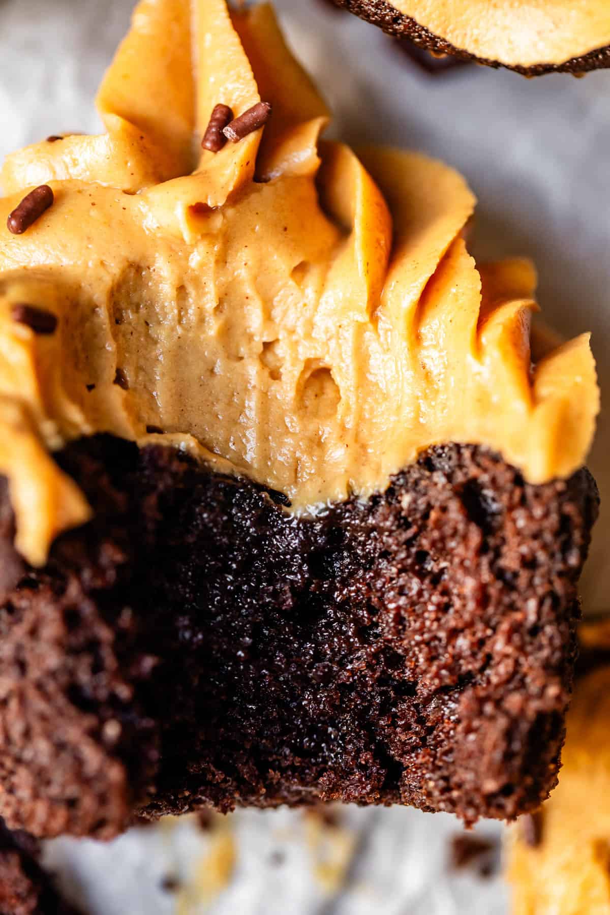 close up photo of a chocolate cupcake topped with peanut butter frosting with a bite taken out.