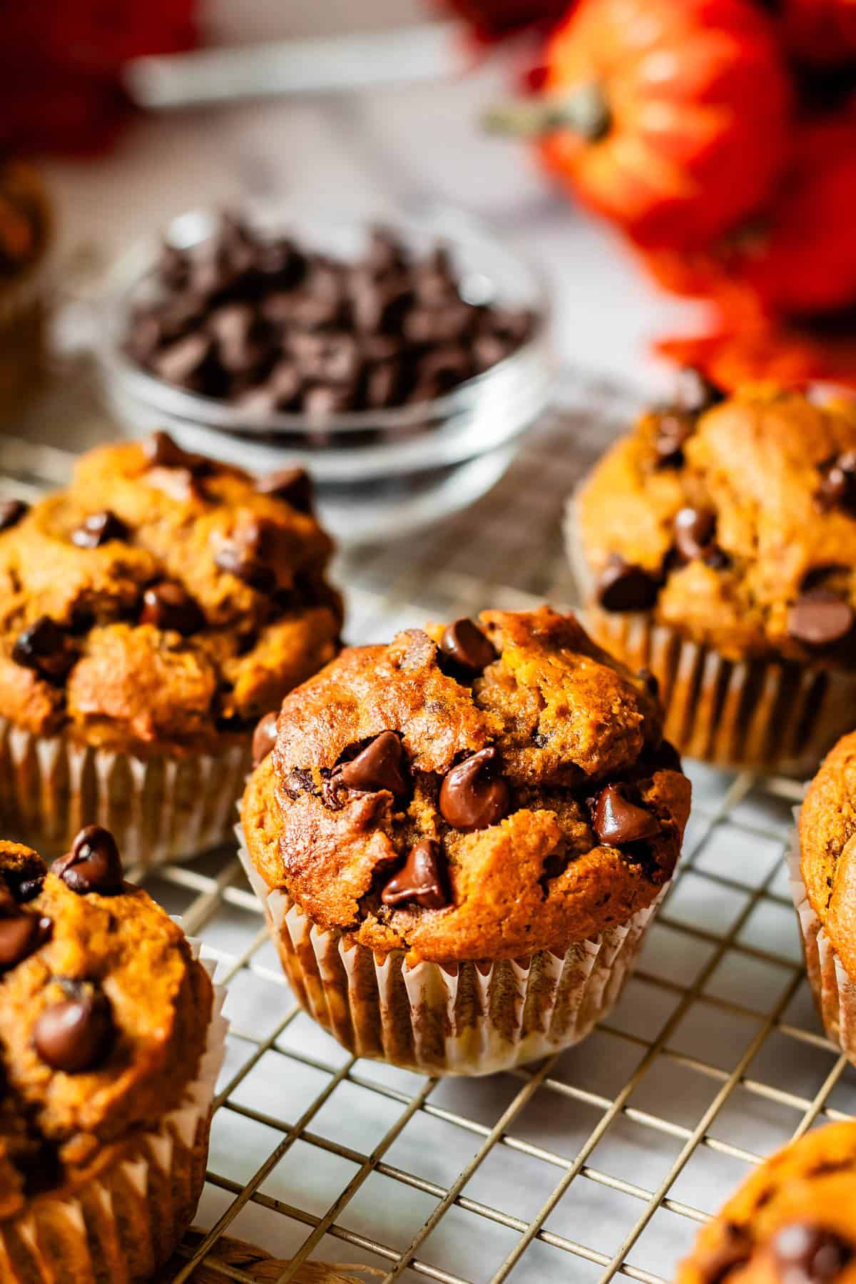 several muffins still in paper liners sitting on a wire cooling rack.