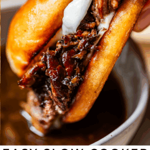 A close-up of a hand holding a French dip sandwich with tender beef and melted cheese in a golden toasted roll, above a bowl of au jus for dipping. Text below reads: Easy Slow Cooker French Dip Sandwiches.