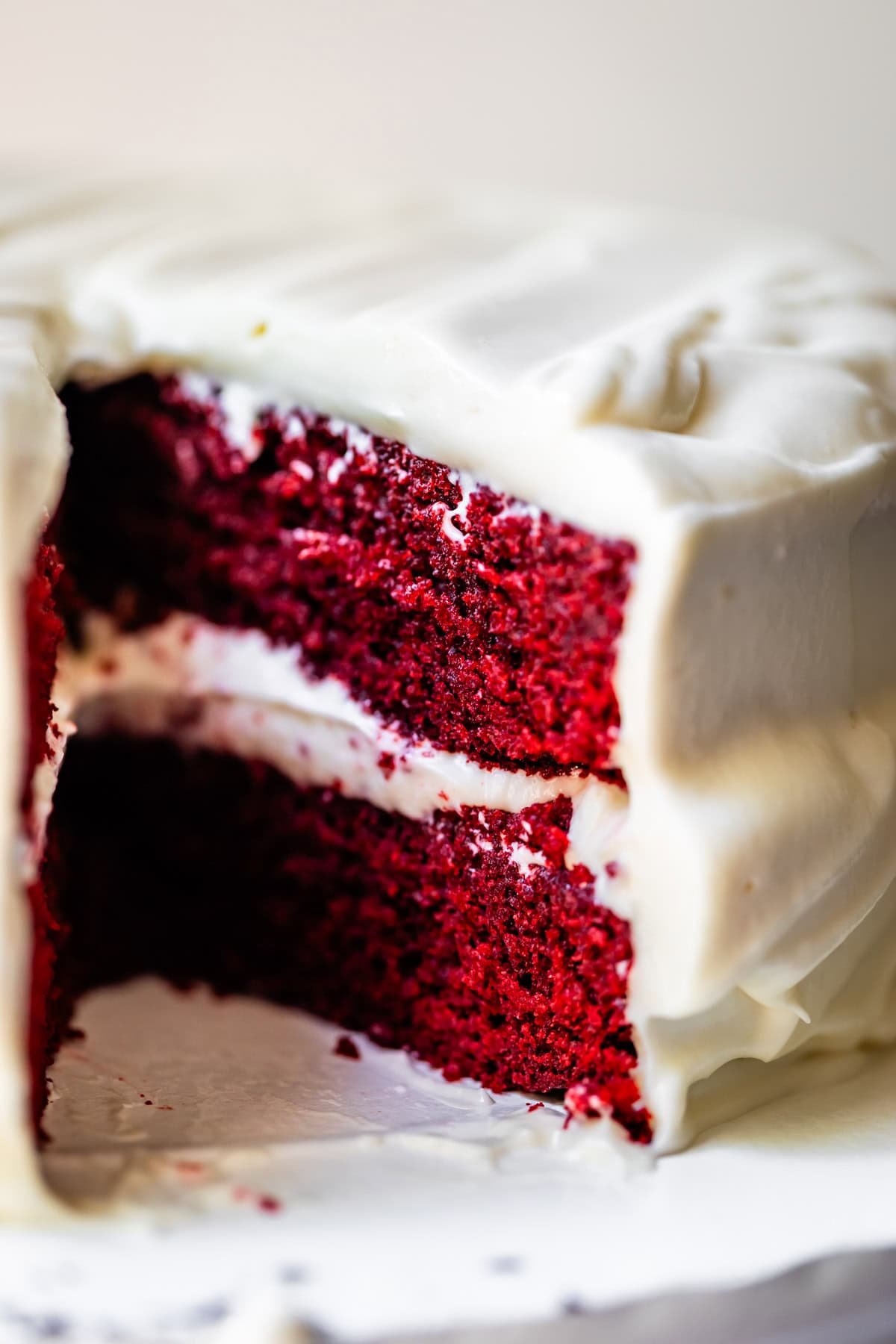 red velvet cake with cream cheese frosting with a slice removed from the cake.