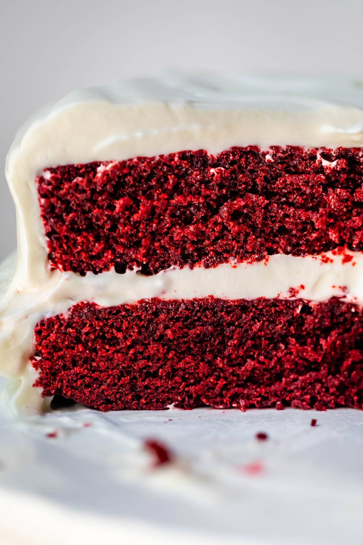 side view of red velvet cake showing two layers with cream cheese frosting in between.