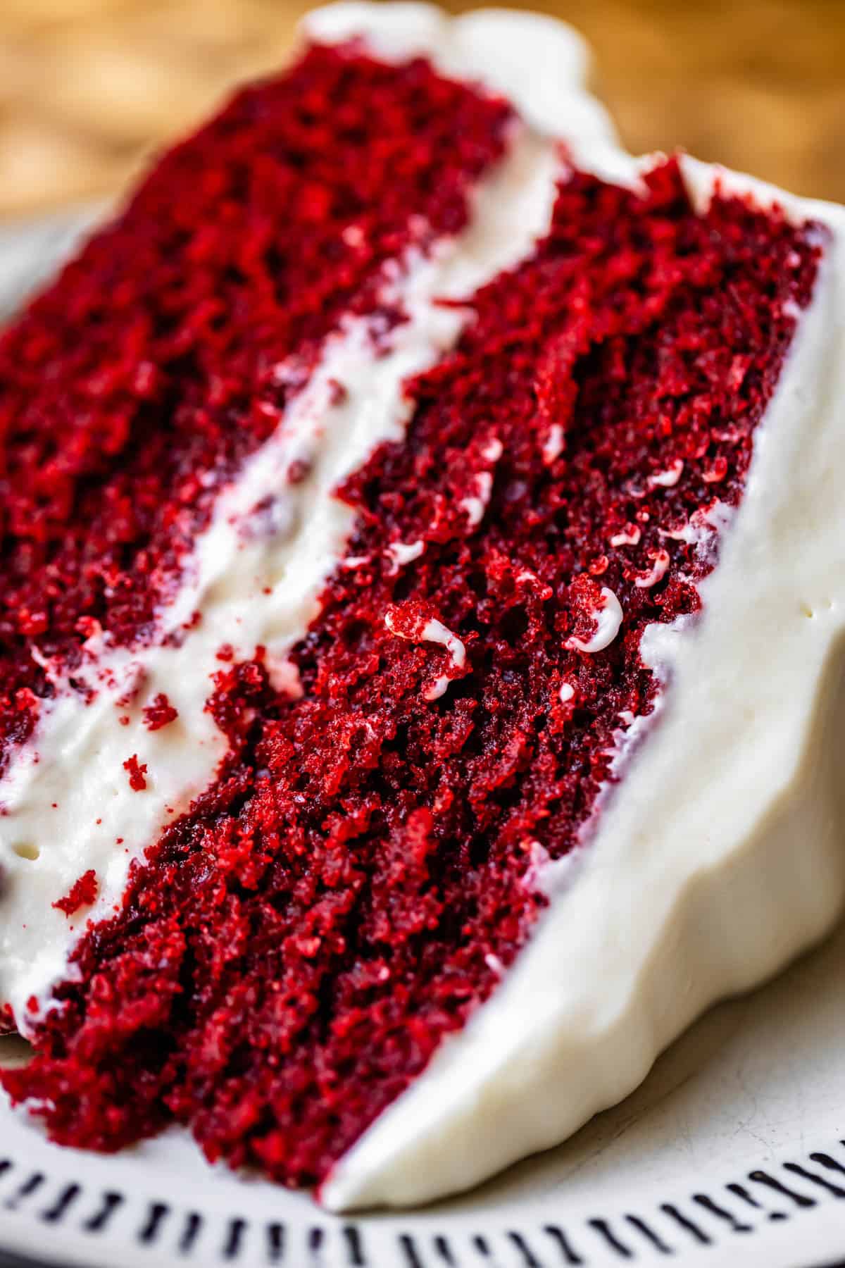 slice of red velvet cake with cream cheese frosting on a plate.