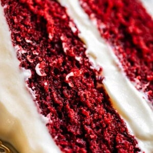 slice of red velvet cake with cream cheese frosting on a plate.