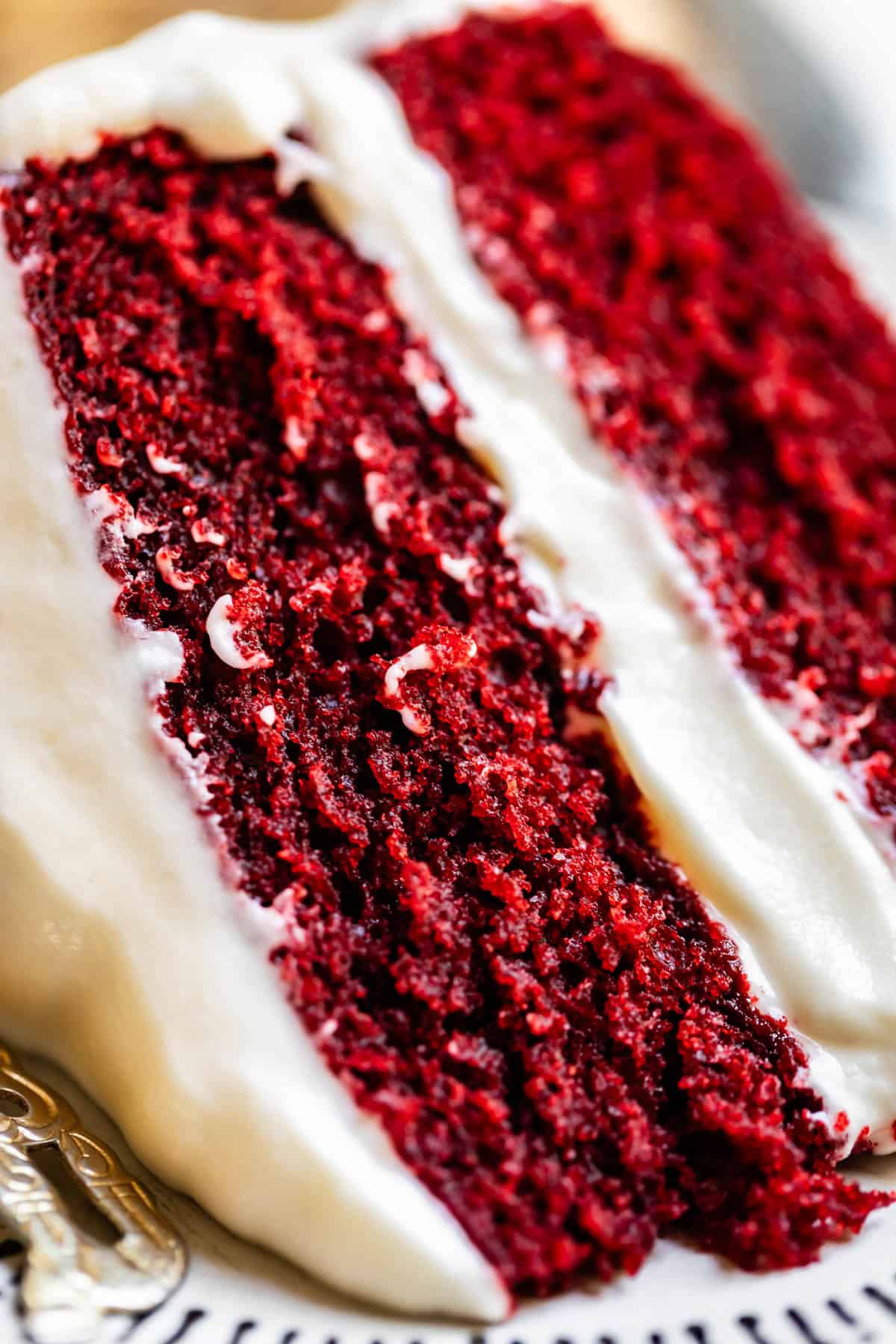 slice of red velvet cake with cream cheese frosting on a plate.