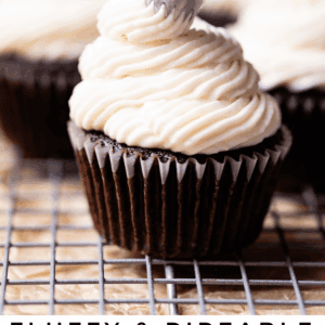 piping whipped cream cheese frosting onto a chocolate cupcake.