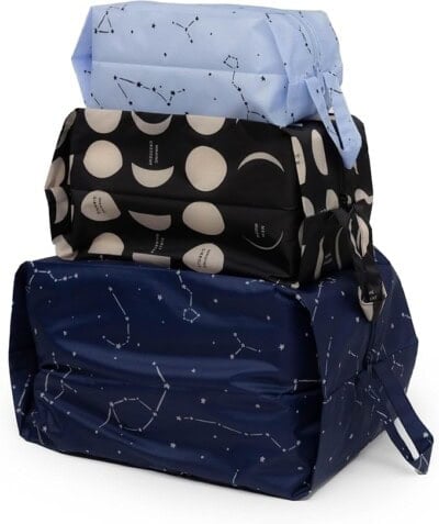 Three rectangular zippered pouches stacked on top of each other; the top one is light blue with constellation patterns, the middle is black with moon phases, and the bottom is dark blue with constellation patterns.