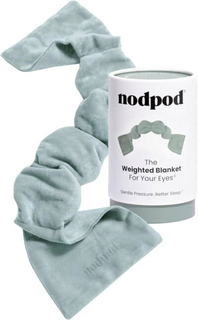 A soft, light green weighted eye blanket is displayed next to its cylindrical packaging labeled nodpod.