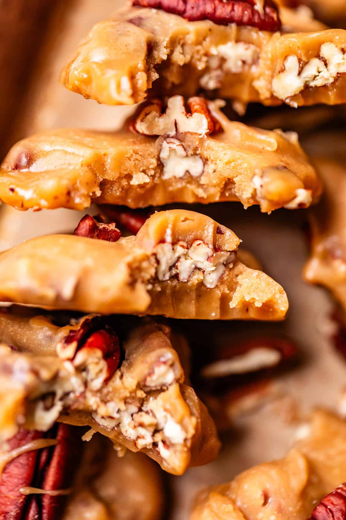 Close-up of stacked pecan pralines, showing their creamy, golden-brown candy texture and crunchy pecan pieces embedded inside.