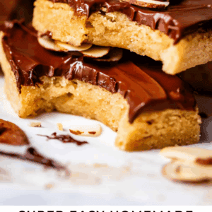 Close-up of homemade almond roca bars topped with chocolate and sliced almonds, stacked on parchment paper, with one bar showing a bite taken out. Text at the bottom reads Super Easy Homemade Almond Roca Bars.